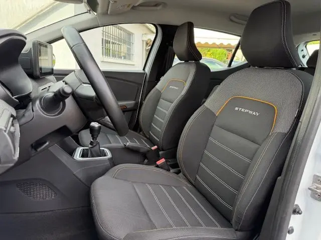 Vue intérieure côté conducteur de la Dacia Sandero Stepway 2021, sièges noirs avec surpiqûres orange et logo Stepway.