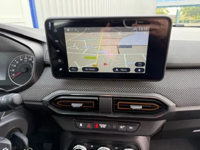 Vue rapprochée de l'écran tactile central avec navigation GPS et aérateurs noirs à liserés orange sur tableau de bord gris.