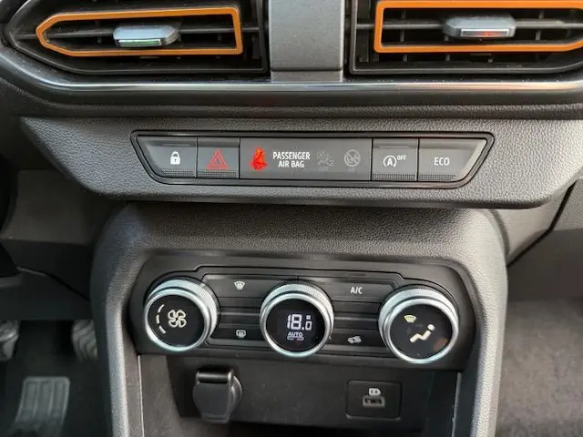 Détail du tableau de bord de la Dacia Sandero Stepway 2021 blanc, avec commandes climatisation à 18°C et voyants activés.