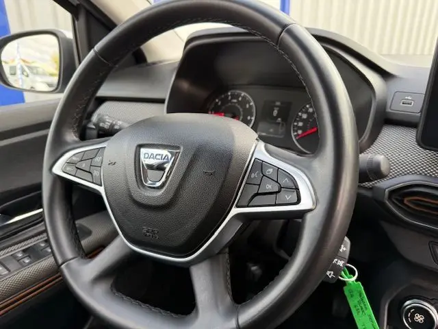 Vue rapprochée du volant noir de la Dacia Sandero Stepway 2021, avec commandes intégrées et tableau de bord en arrière-plan.