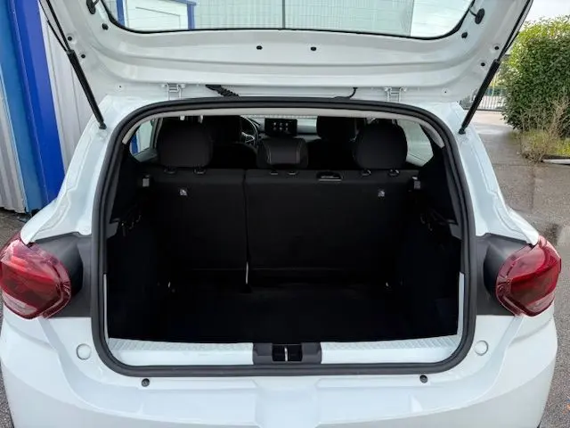 Coffre ouvert vu de l'arrière d'une Dacia Sandero Stepway blanche 2021, montrant l'espace de chargement et les sièges arrière noirs.