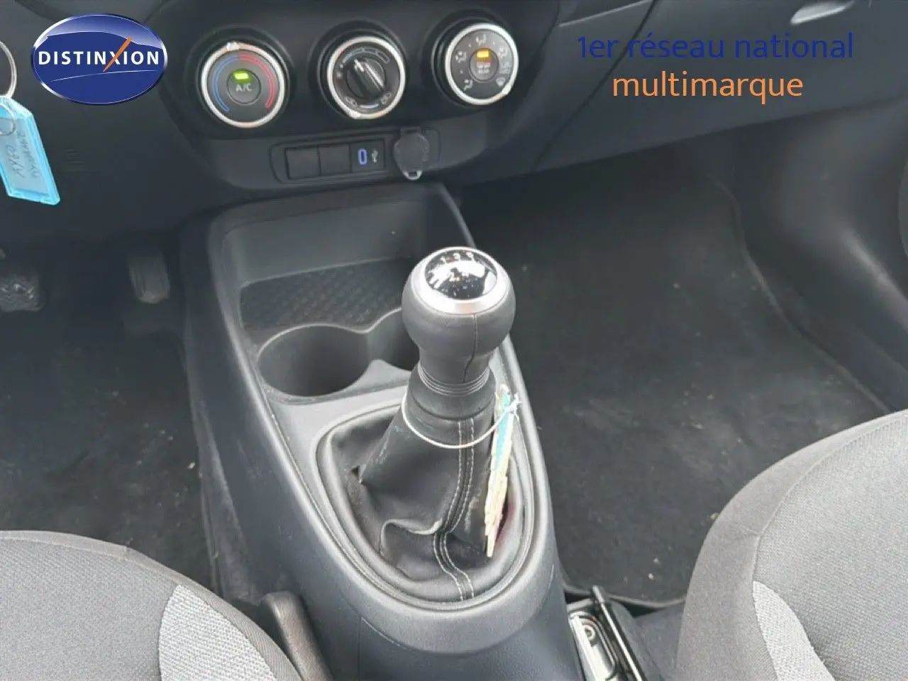 Gros plan sur la console centrale d'une Toyota Aygo X noire 2025, mettant en valeur le levier de vitesse manuel et les commandes de climatisation.