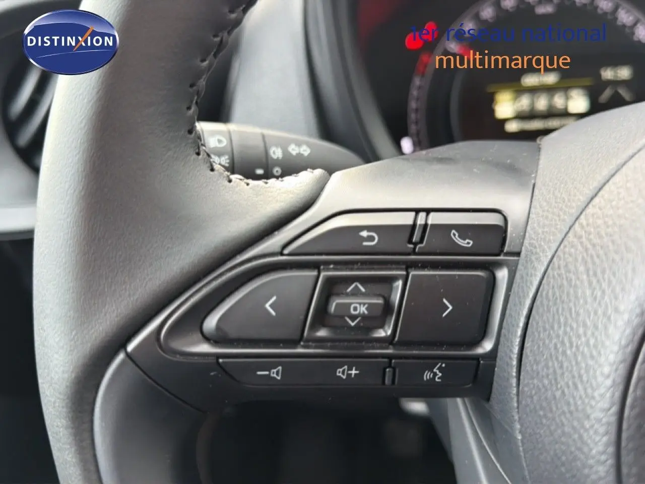 Gros plan sur les commandes au volant côté gauche d'une Toyota Aygo X noire, avec boutons multifonctions visibles.