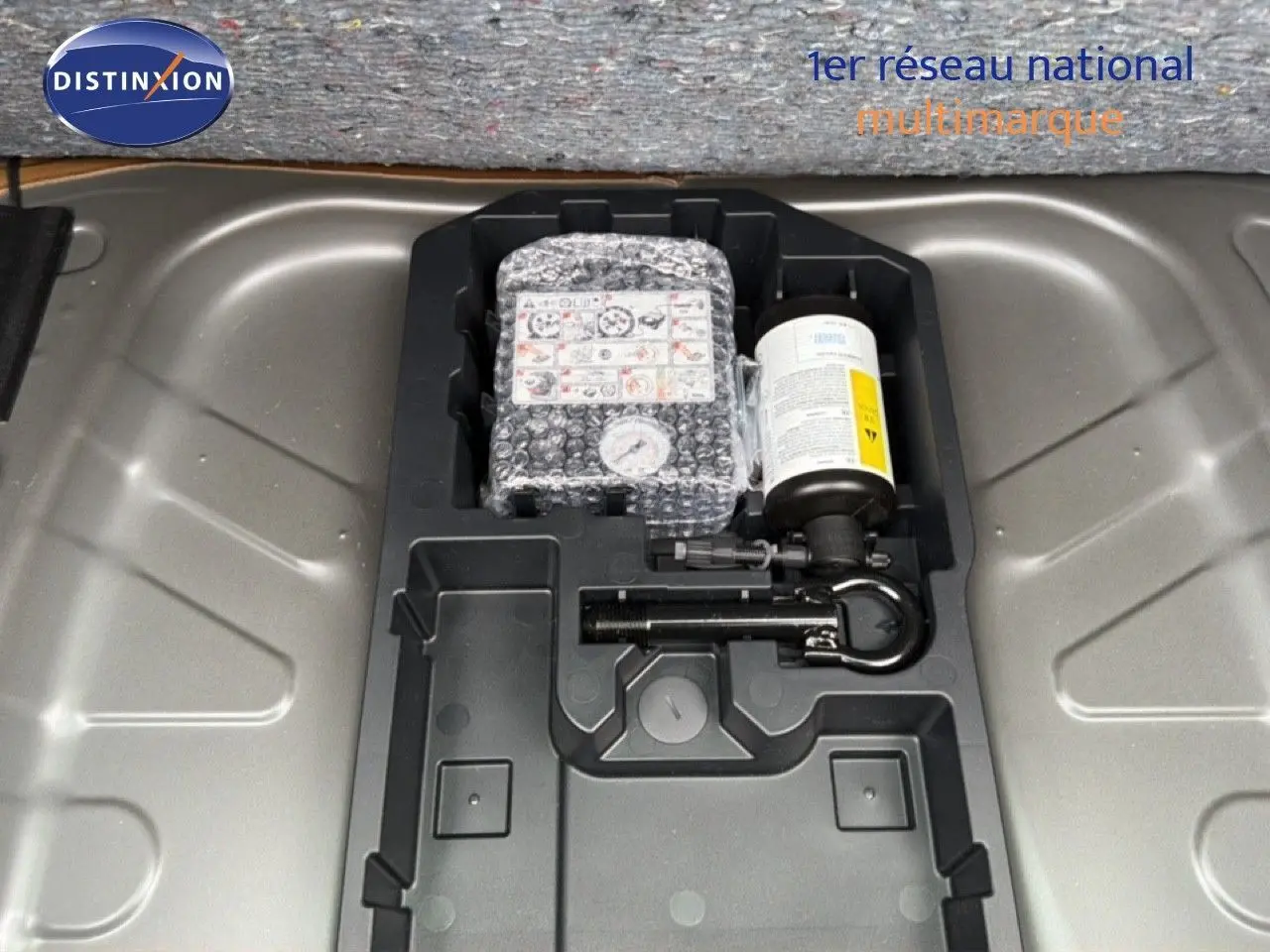 Gros plan sur le rangement sous coffre de la Toyota Aygo X 2025, montrant le kit de réparation pneus intégré.