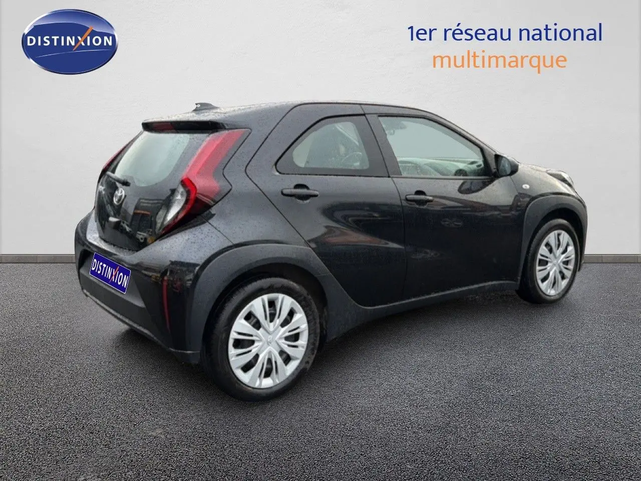 Vue 3/4 arrière droite d'une Toyota Aygo X noire 2025 avec feux arrière en forme de C et jantes argentées.