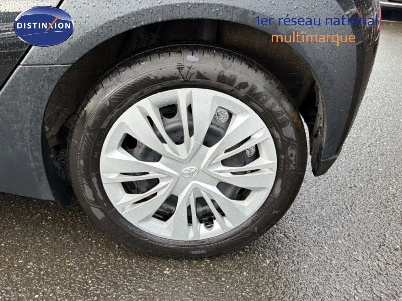 Gros plan sur la roue avant droite noire d’une Toyota Aygo X 2025 avec jante en alliage argentée et logo Toyota.