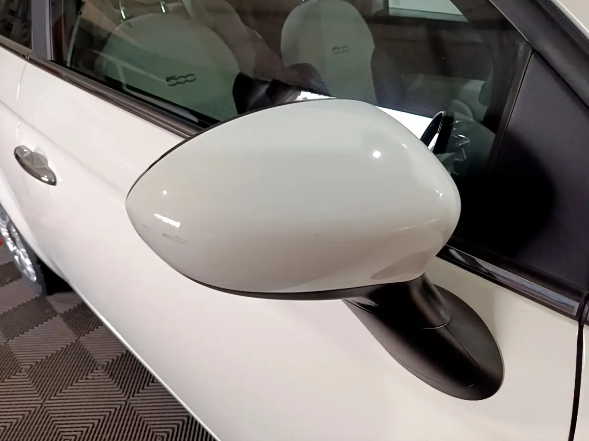 Rétroviseur blanc côté gauche d'une Fiat 500 Hybrid 2021, avec porte et siège intérieur visibles.