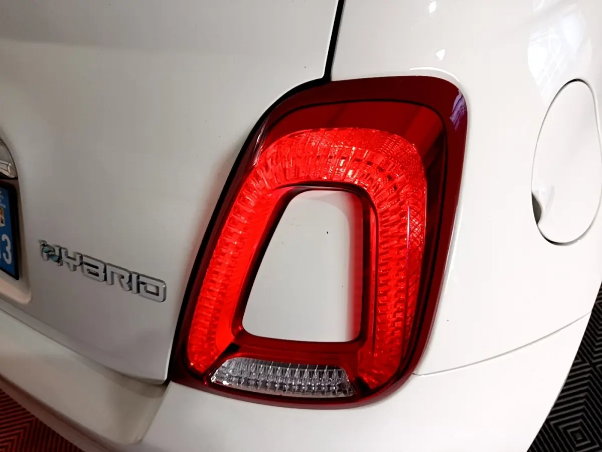 Gros plan sur le feu arrière droit rouge et blanc d'une FIAT 500 Hybrid blanche, avec le logo Hybrid visible sur l'aile arrière.