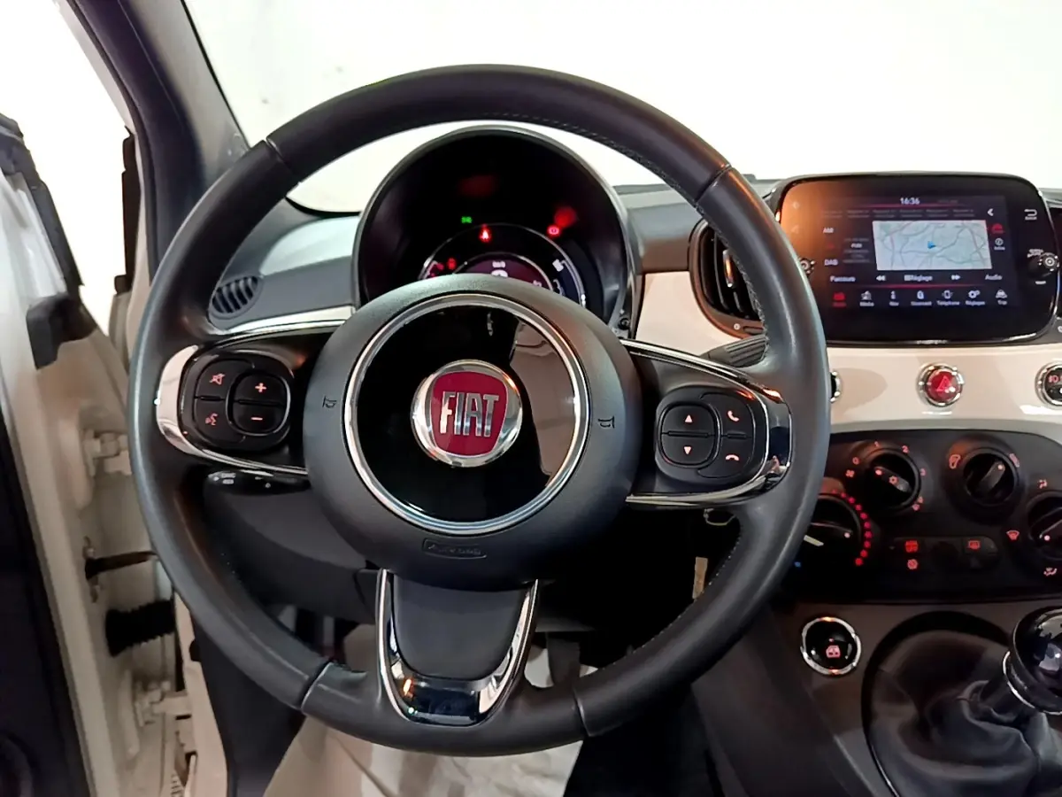 Vue intérieure centrée sur le volant cuir noir et le tableau de bord blanc de la Fiat 500 Hybrid 2021.
