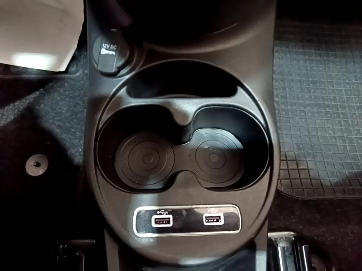 Gros plan sur les porte-gobelets et les ports USB avant de la Fiat 500 Hybrid blanche de 2021.
