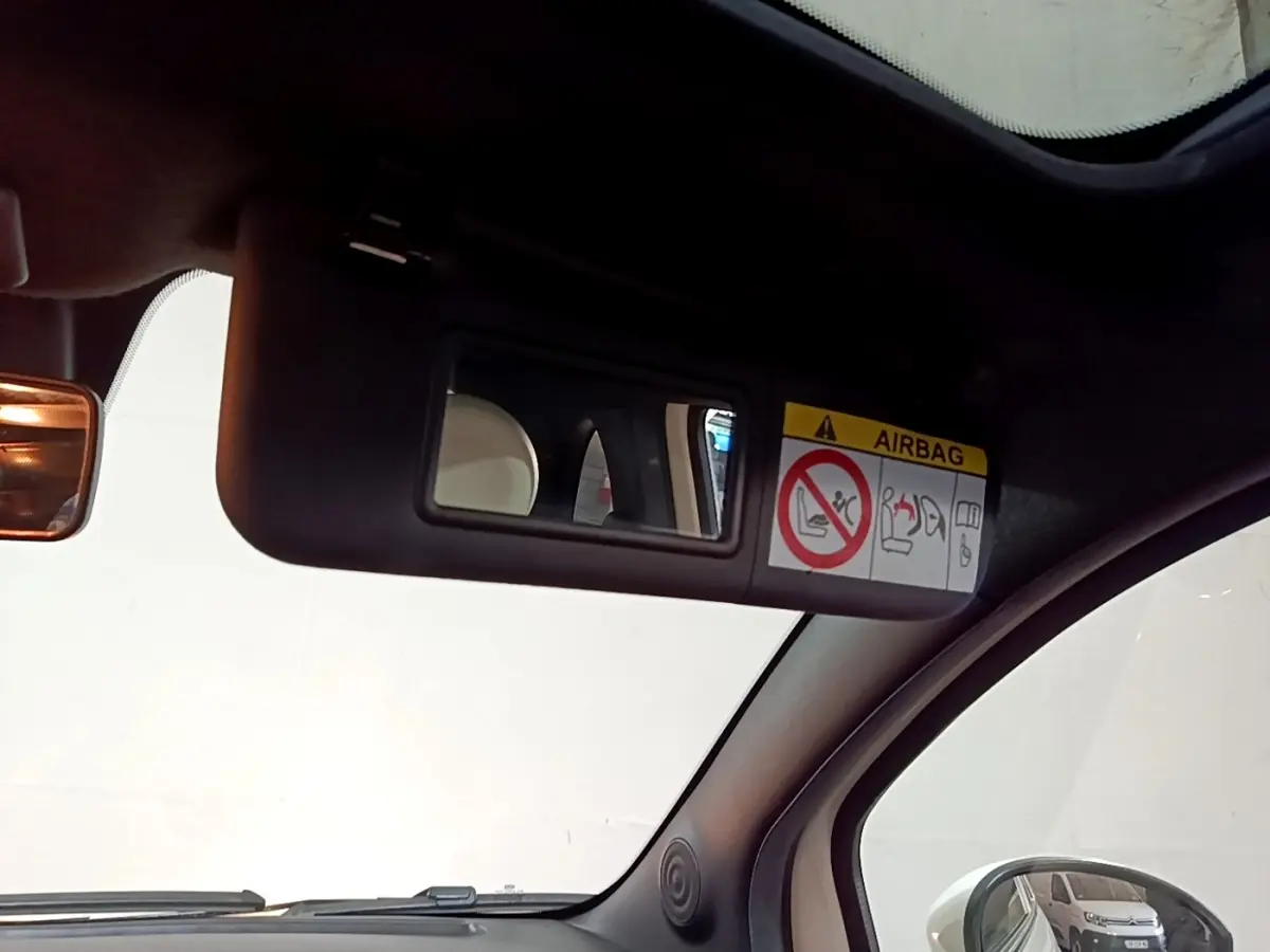 Intérieur de la Fiat 500 Hybrid 2021, vue du pare-soleil côté conducteur avec miroir et avertissement airbag visible.