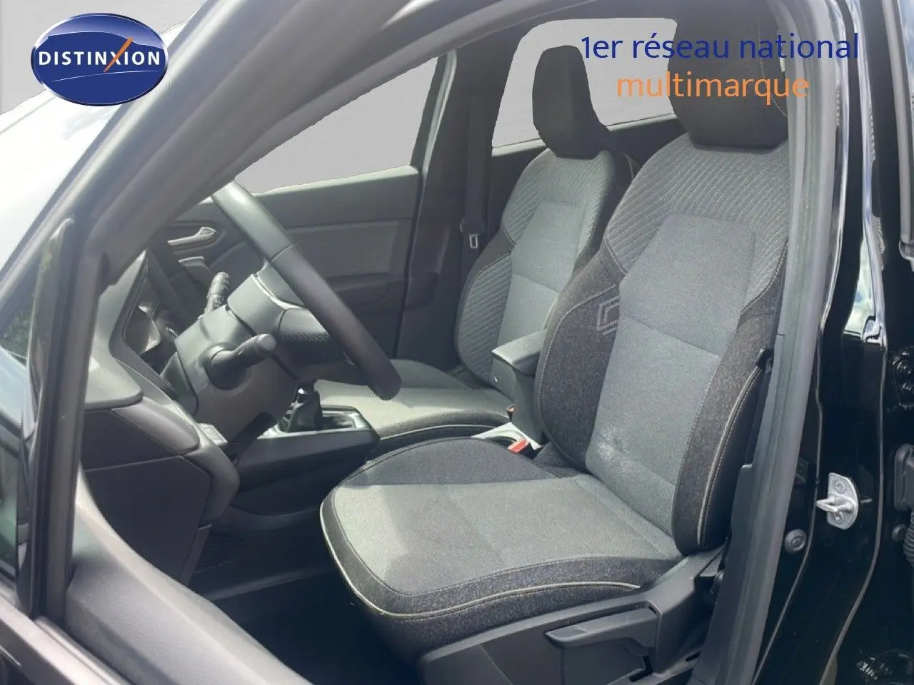 Intérieur du Renault Captur 2025 vu côté gauche, sièges tissu gris et noir, volant et levier de vitesse manuelle visibles.