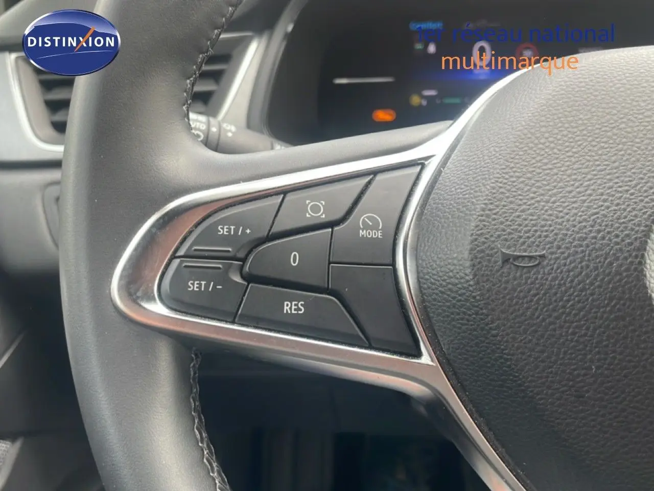 Gros plan sur les commandes de régulateur de vitesse au volant d’un Renault Captur noir étoile métal avec toit gris.