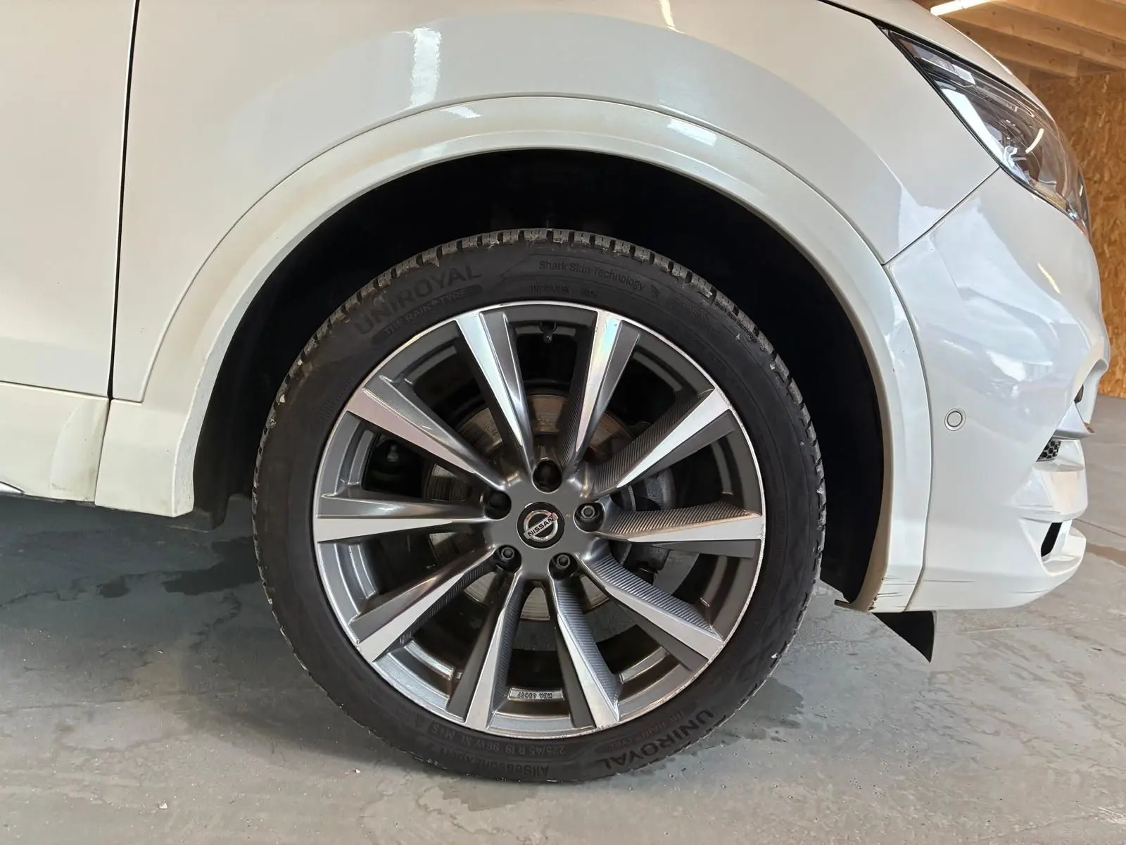 Gros plan sur la roue avant droite du Nissan Qashqai blanc 2021, mettant en valeur la jante alliage et le pneu UniRoyal.