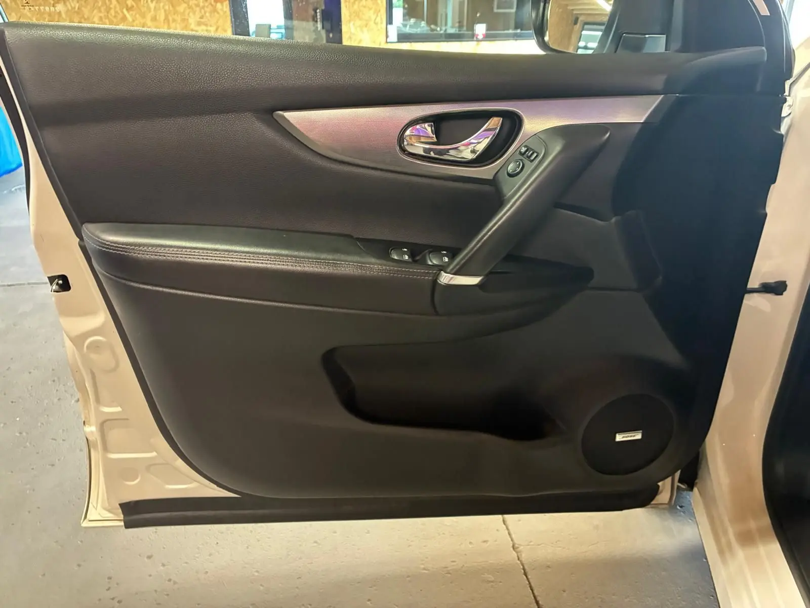 Vue intérieure de la porte avant gauche du Nissan Qashqai blanc, avec garniture noire et haut-parleur Bose intégré.