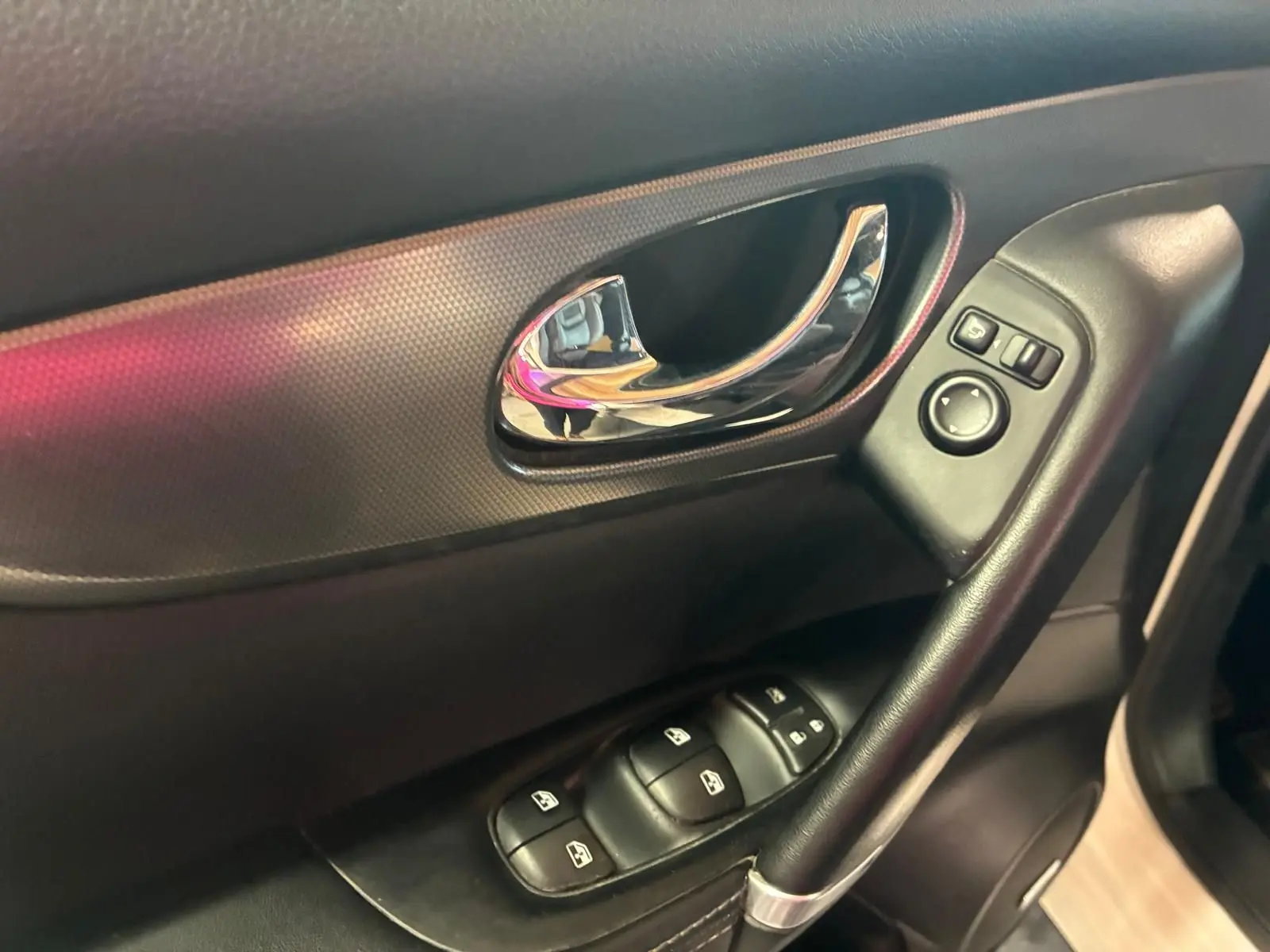 Gros plan sur la poignée intérieure et les commandes des vitres côté conducteur du Nissan Qashqai blanc, finition Tekna+ 2021.