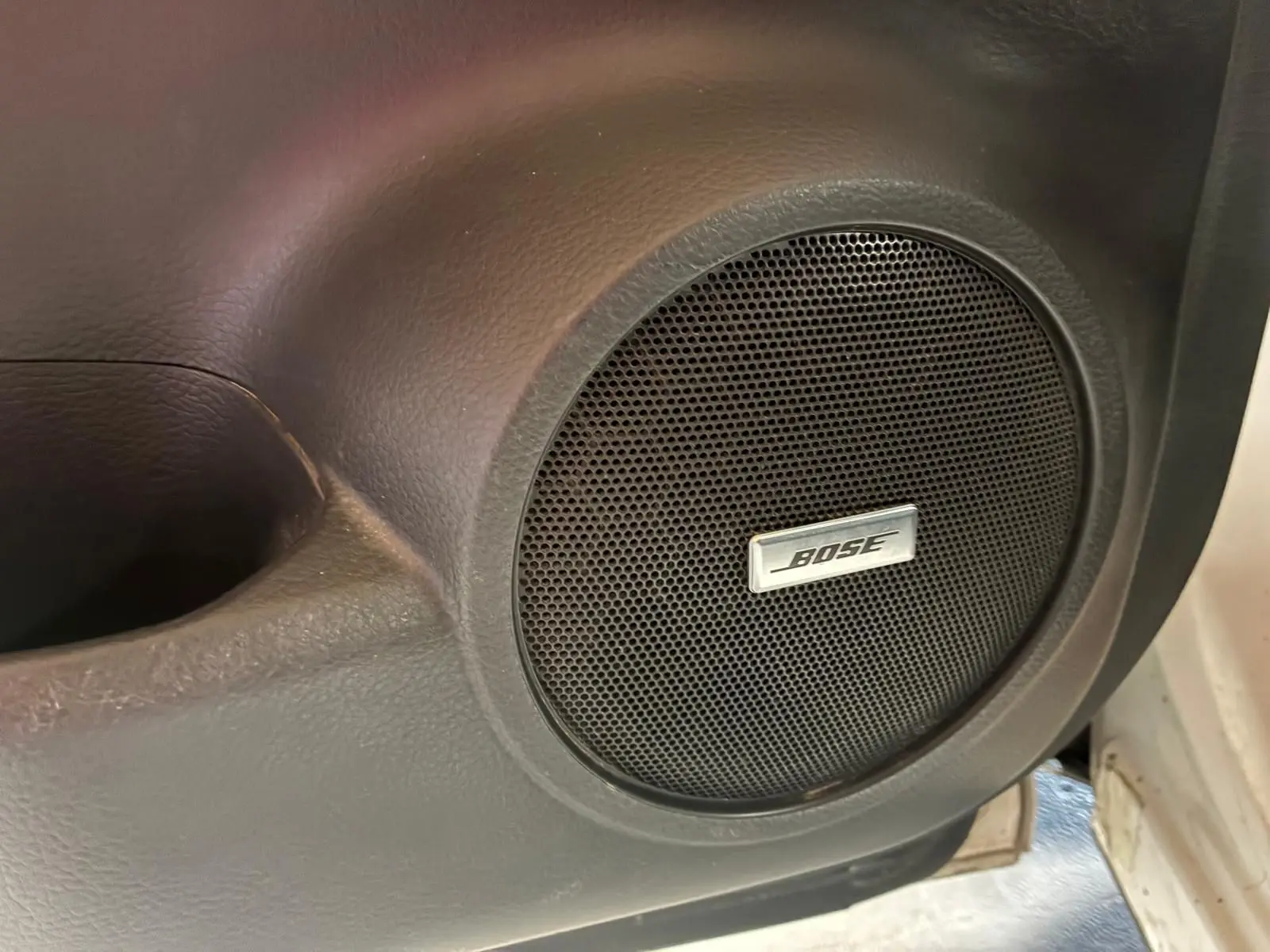 Gros plan sur l'enceinte Bose intégrée à la porte intérieure noire d'un Nissan Qashqai blanc, version Tekna+ 2021.