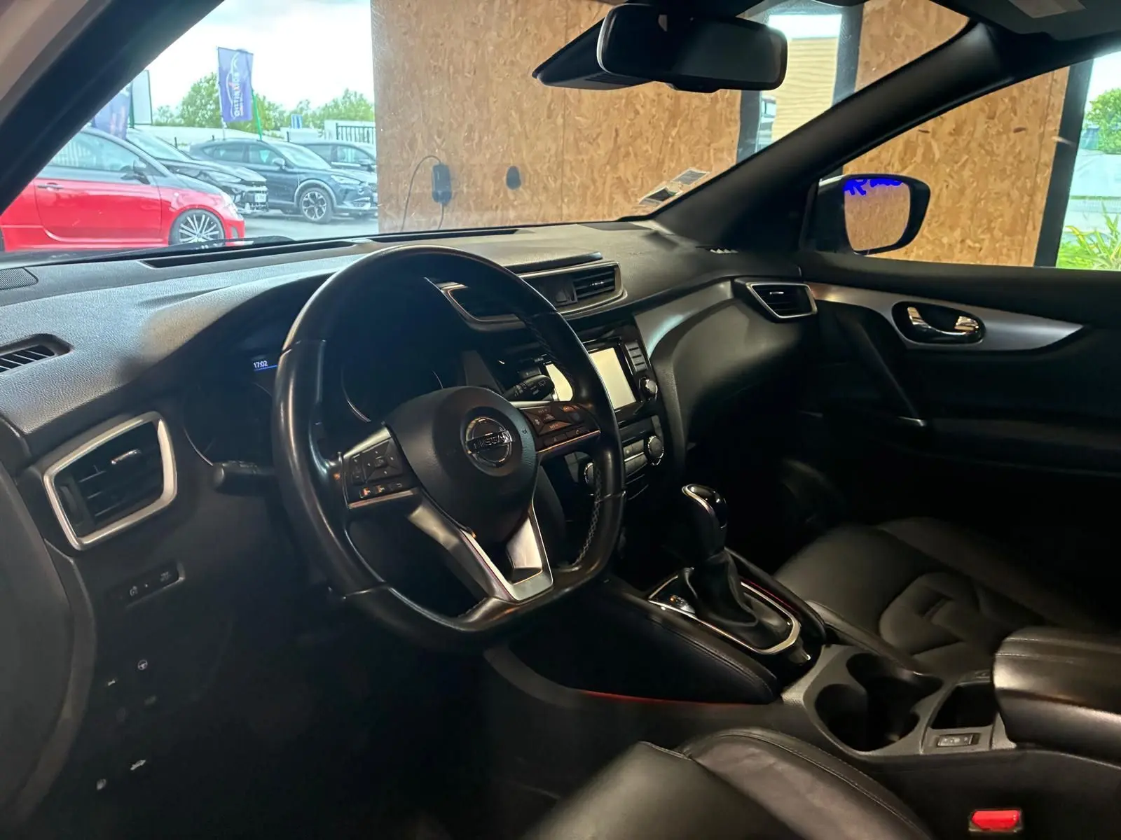 Vue intérieure côté conducteur du Nissan Qashqai blanc 2021, tableau de bord et volant en cuir noir visibles.