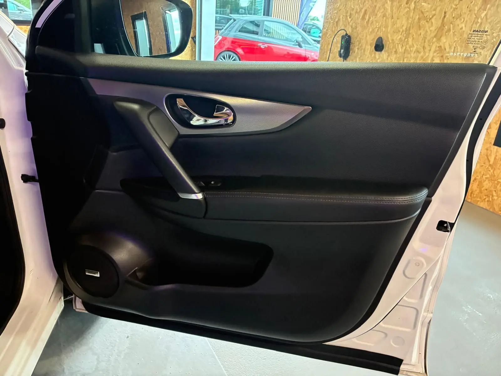 Vue intérieure de la porte avant gauche blanche du Nissan Qashqai 1.5 BlueDCI Tekna+ avec garniture noire et poignée chromée.