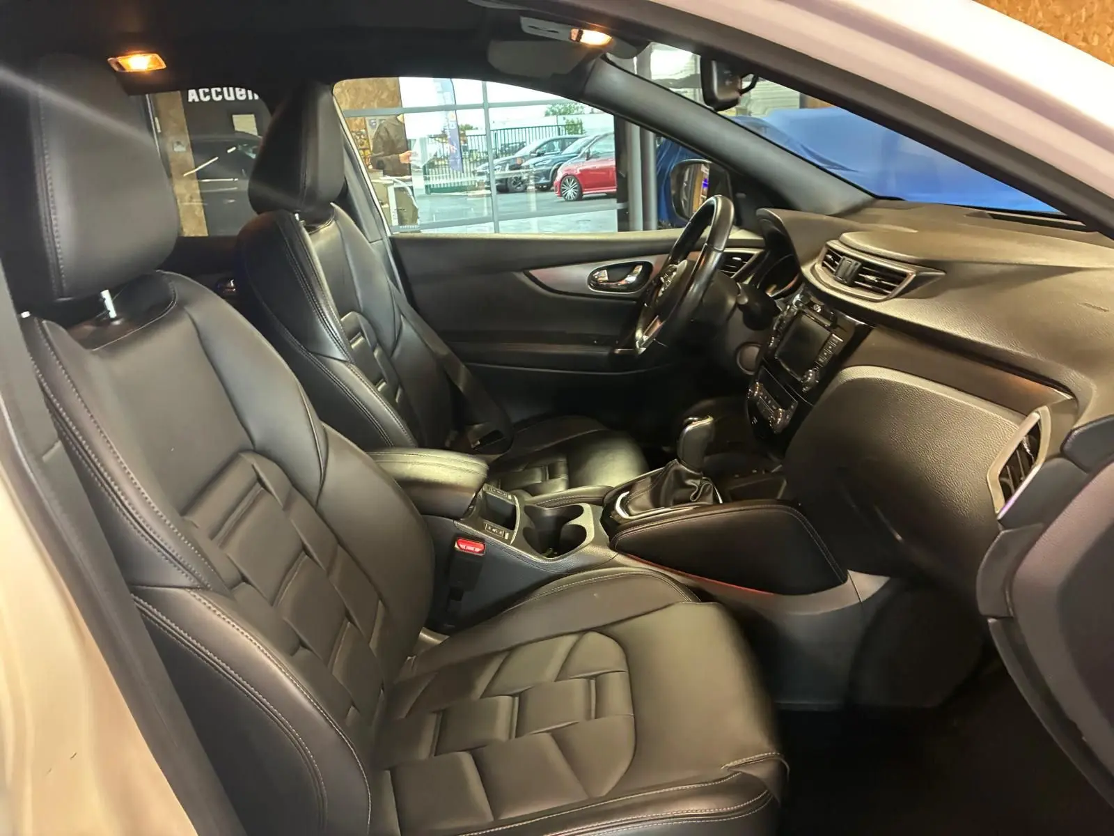 Intérieur noir cuir du Nissan Qashqai 1.5 BlueDCI 115 Tekna+, vue côté conducteur avec tableau de bord et console centrale.