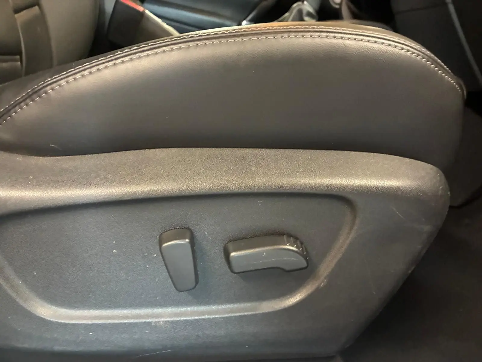 Détail des commandes électriques de réglage du siège avant en cuir noir du Nissan Qashqai blanc 2021.