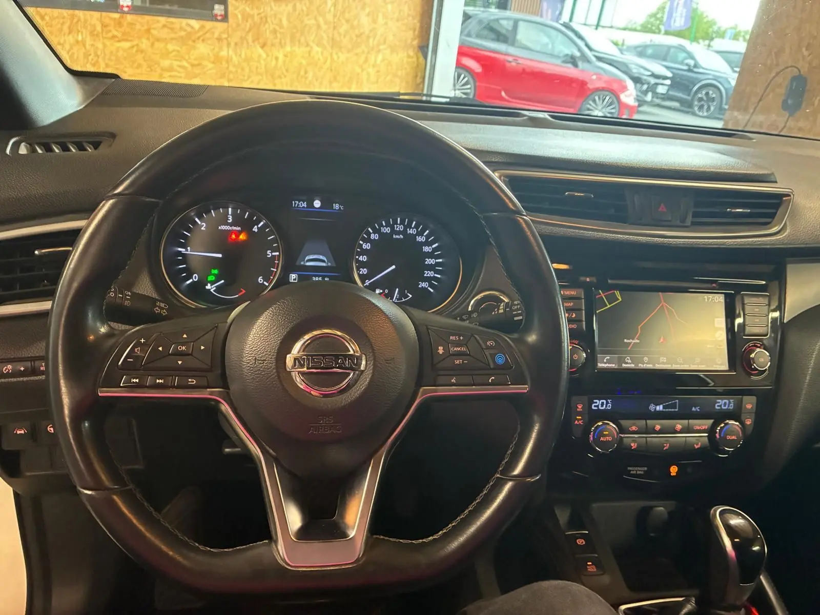 Vue intérieure centrée sur le volant cuir noir et le tableau de bord avec écran tactile du Nissan Qashqai blanc 2021.