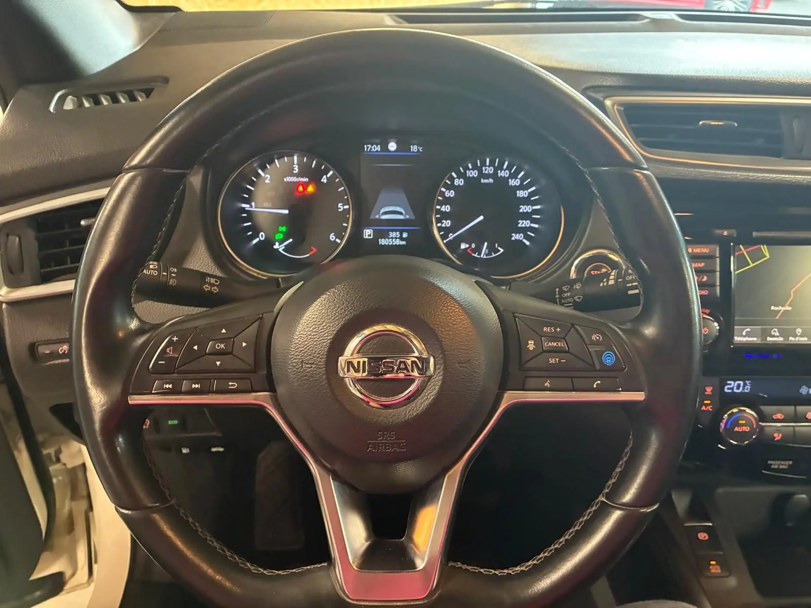 Vue rapprochée du volant en cuir noir du Nissan Qashqai 1.5 BlueDCI 115 Tekna+ avec tableau de bord et écran GPS visibles.