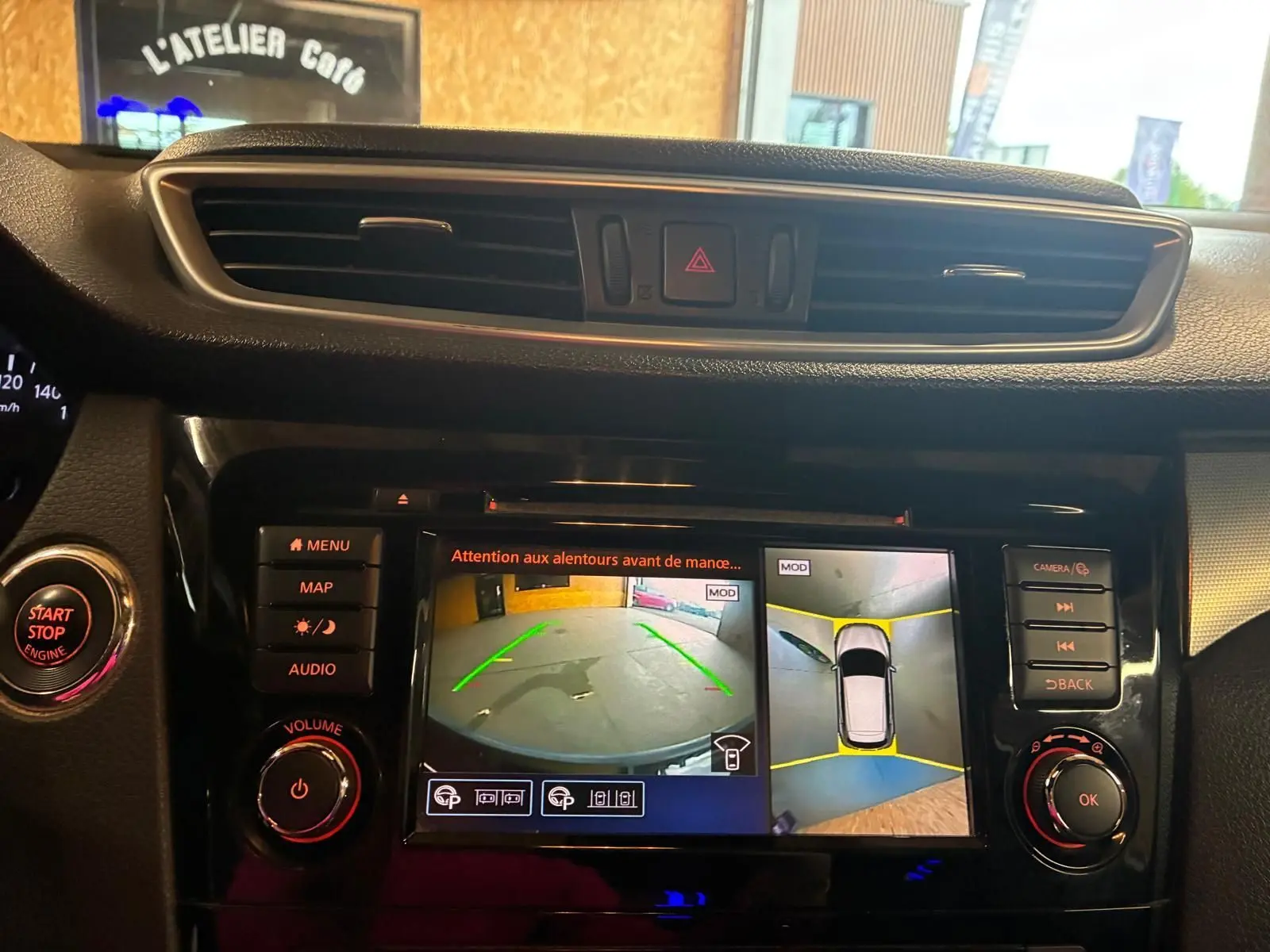 Vue rapprochée de l’écran central du Nissan Qashqai blanc 2021 montrant la caméra de recul et l’alerte de proximité.