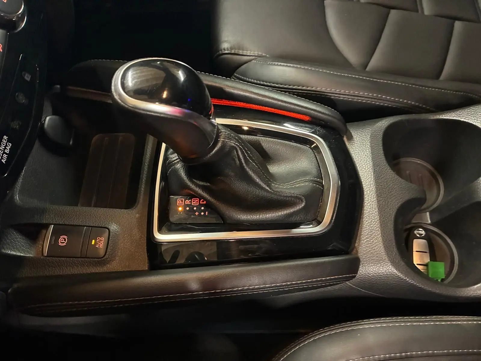 Gros plan sur la console centrale du Nissan Qashqai blanc 2021, mettant en valeur le levier de vitesse automatique et les commandes environnantes.