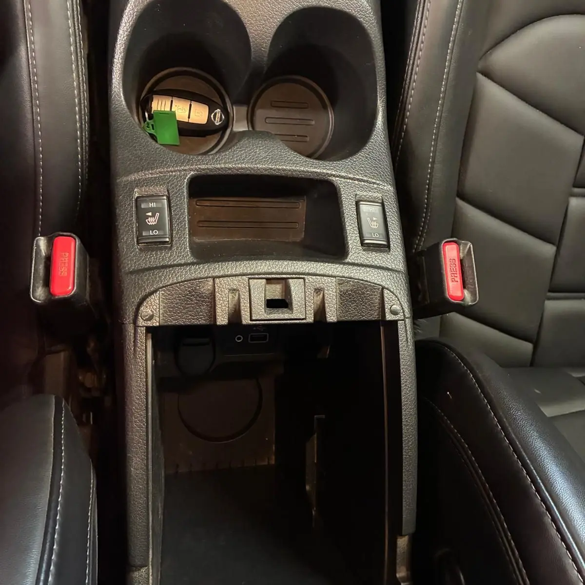Vue plongeante sur la console centrale noire du Nissan Qashqai 1.5 BluedCi 115 Tekna+ avec porte-gobelets et sièges cuir chauffants.