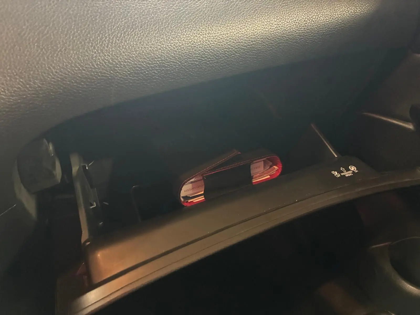 Gros plan sur la boîte à gants ouverte du Nissan Qashqai blanc 2021, montrant un carnet rouge à l'intérieur.