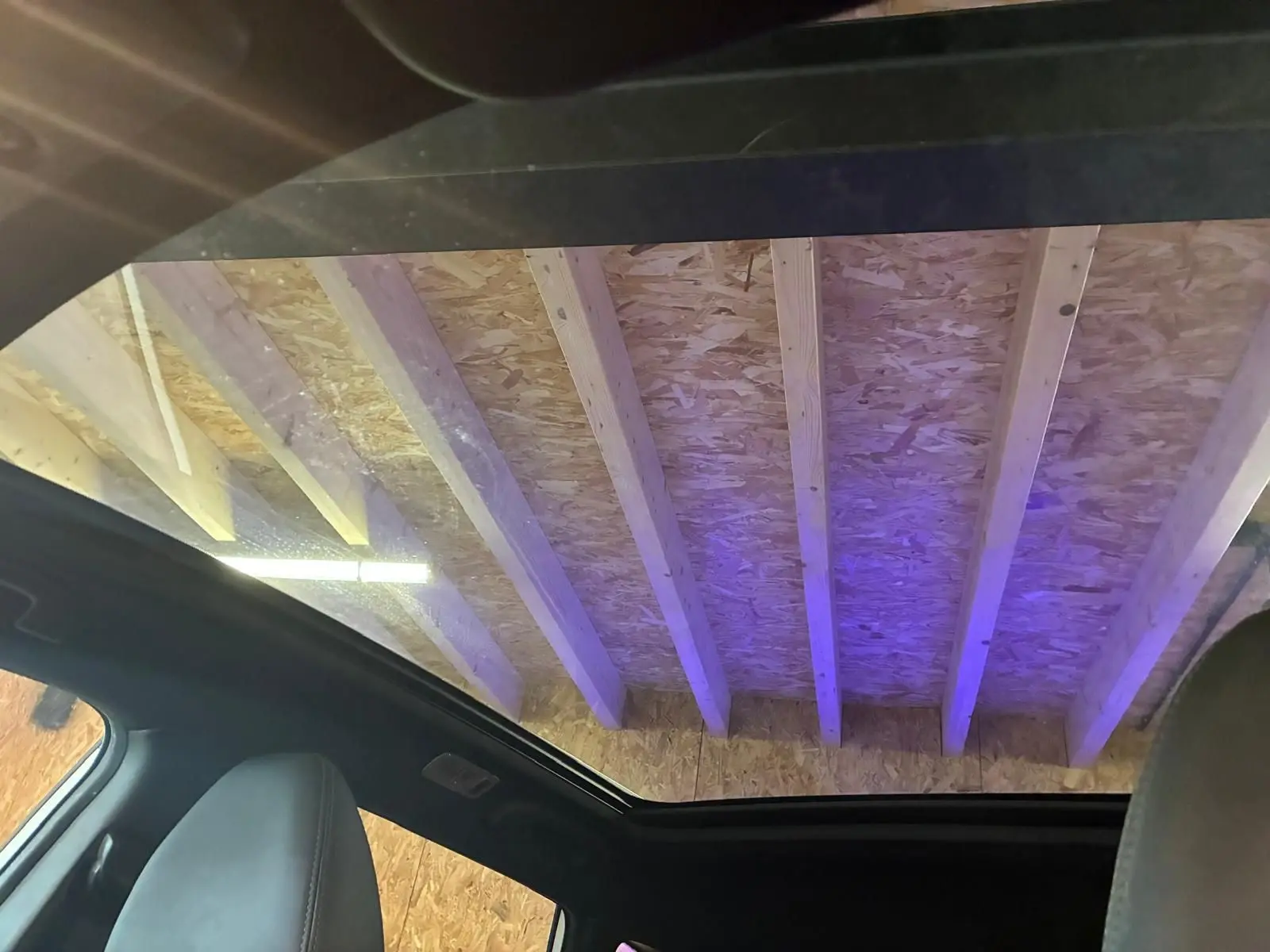 Toit panoramique ouvert vu de l'intérieur du Nissan Qashqai blanc 2021, avec sièges en cuir noir visibles.