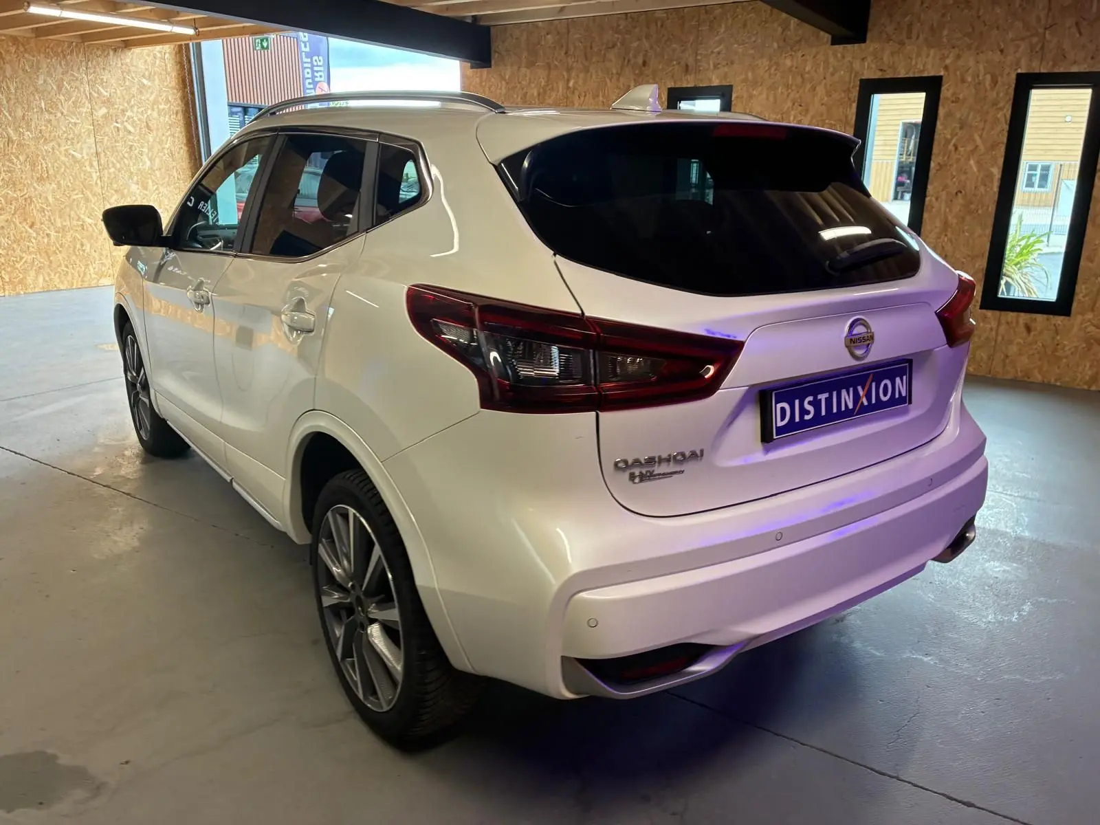 Vue 3/4 arrière droite du Nissan Qashqai blanc 1.5 BlueDCI Tekna+ 2021 avec feux arrière LED et toit noir.