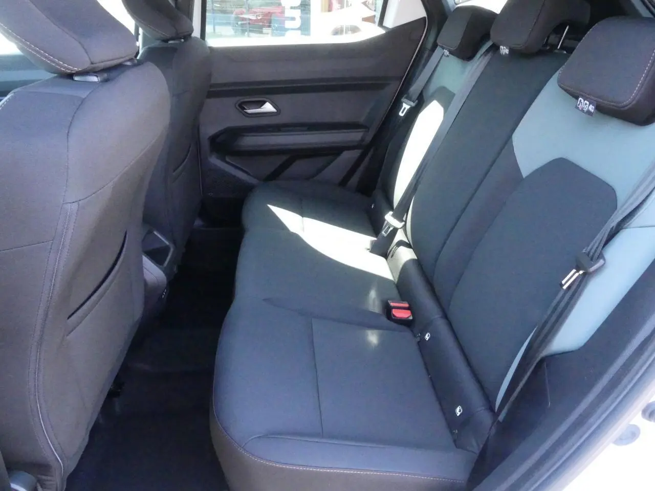 Vue intérieure côté droit sur la banquette arrière noire et grise du Dacia Duster 1.6 Hybrid blanc Glacier 2025.