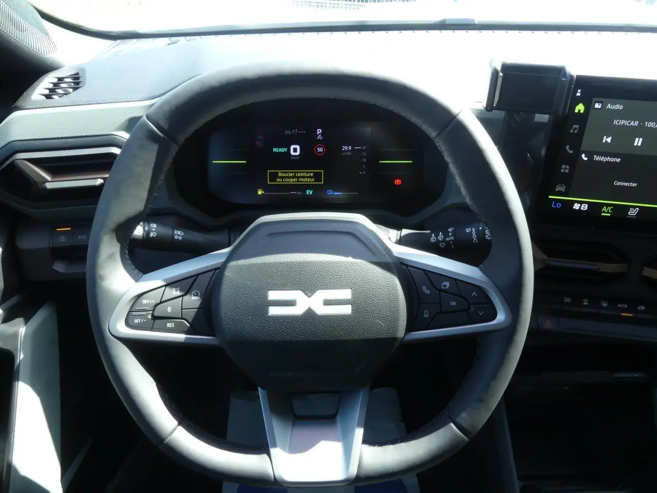 Vue rapprochée du volant noir du Dacia Duster 2025 hybride avec commandes intégrées et tableau de bord digital.