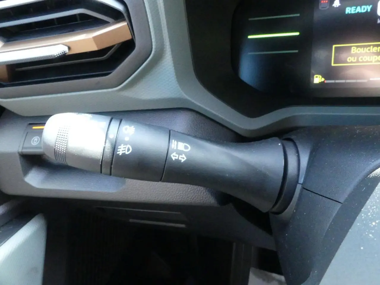 Gros plan sur la commande de clignotants et feux du tableau de bord du Dacia Duster blanc 2025.