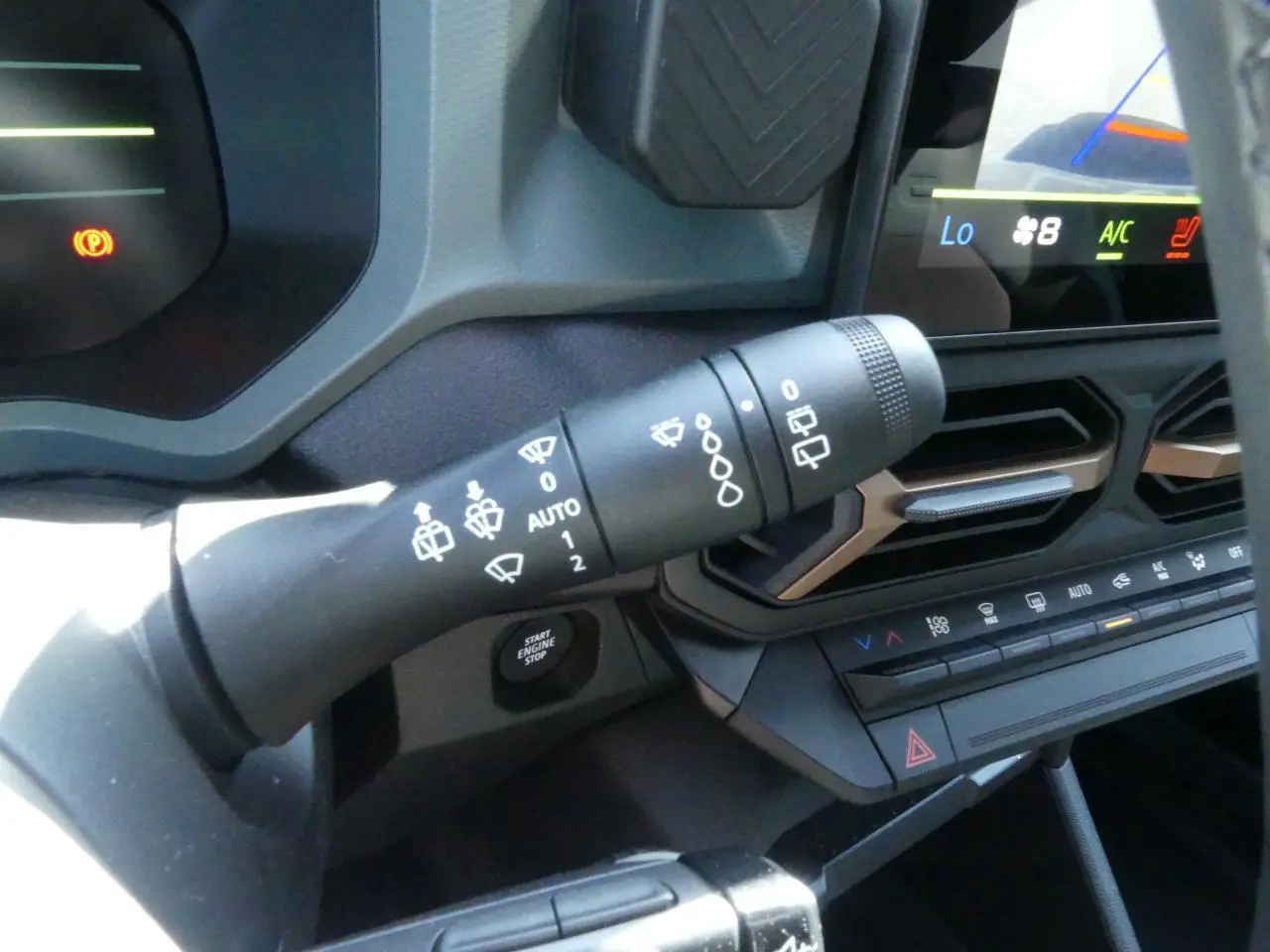 Gros plan sur la commande d'essuie-glace et la console centrale noire avec détails brun cuivré du tableau de bord du Dacia Duster blanc.