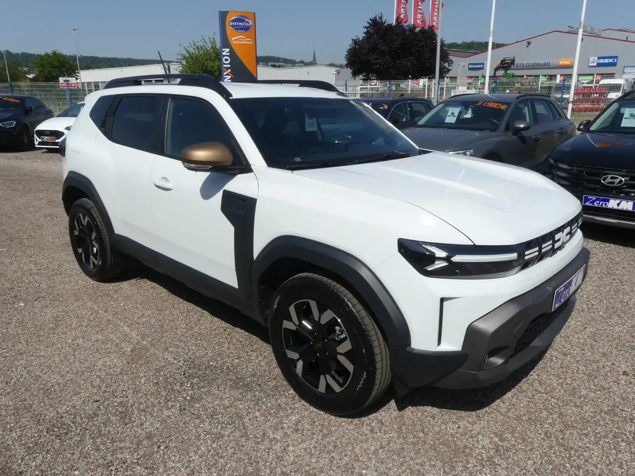 Vue 3/4 avant droite d'un Dacia Duster blanc avec coques de rétroviseurs brun cuivré et jantes alliage noires.