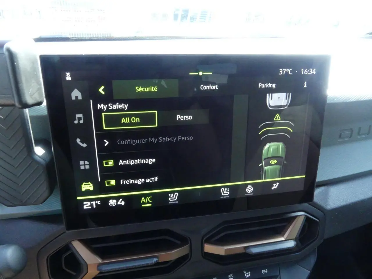 Écran tactile central du Dacia Duster 2025 affichant les options de sécurité et confort, avec détails en vert et noir.