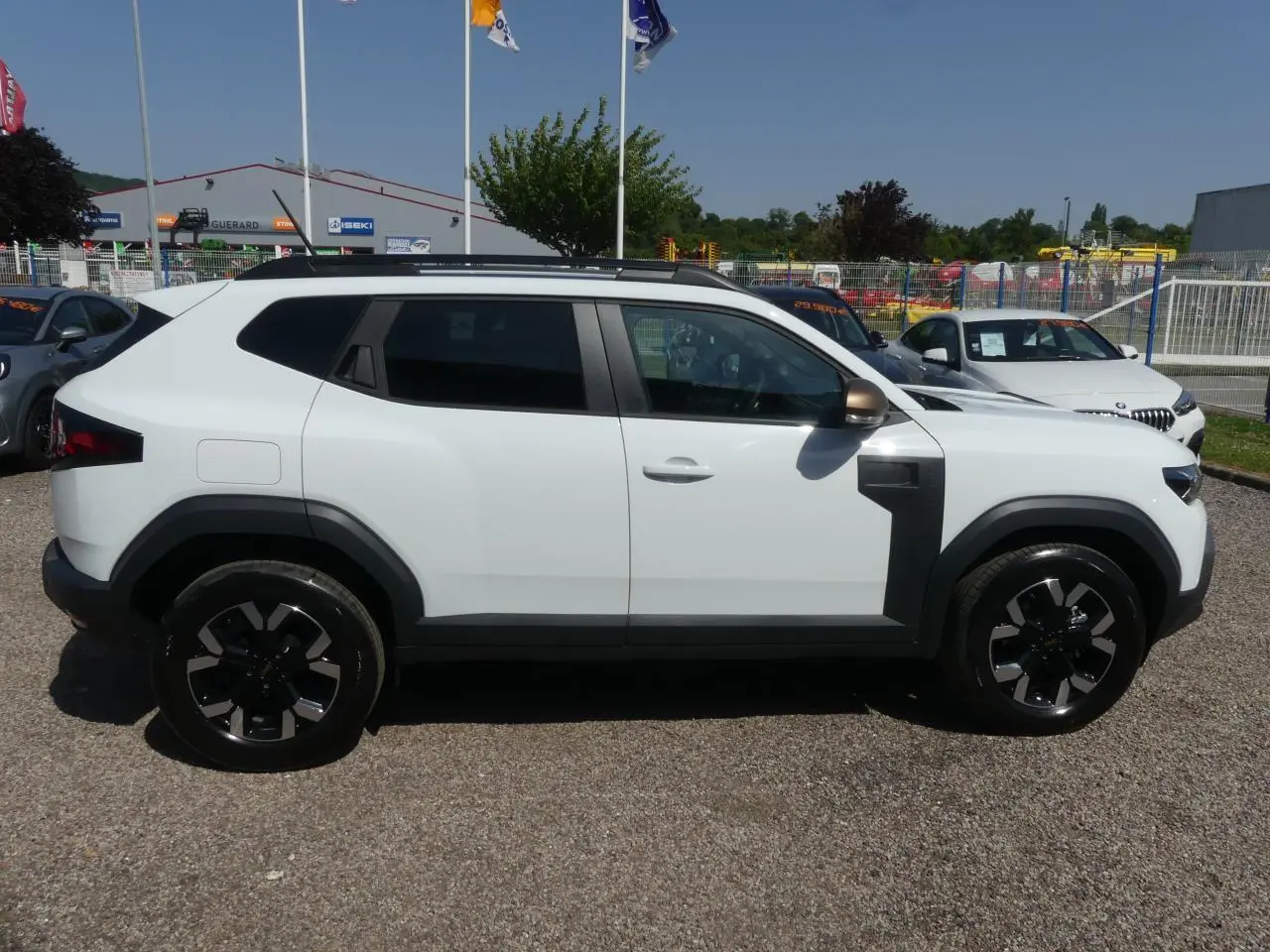 Profil côté gauche du Dacia Duster blanc Glacier 2025 avec jantes alliage noires et détails noirs contrastants.