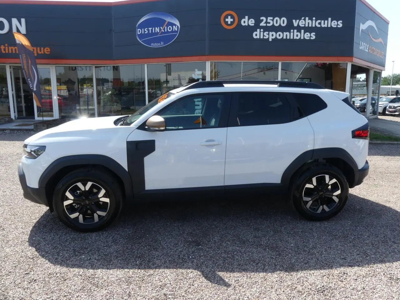 Profil côté gauche d'un Dacia Duster blanc Glacier 2025 avec jantes alliage et détails noirs contrastants.