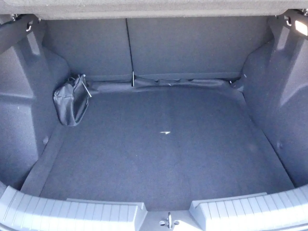 Coffre vide du Dacia Duster blanc 1.6 Hybrid 2025, vue intérieure arrière avec revêtement noir.