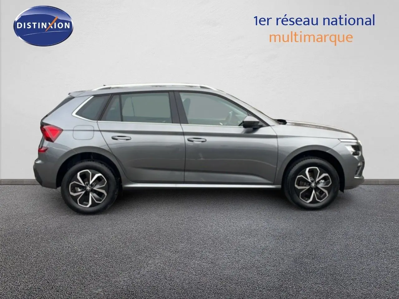 Profil côté droit d'un Skoda Kamiq 2025 gris graphite métallisé avec jantes bi-ton et toit équipé de barres de toit.