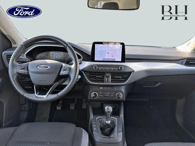 Vue intérieure avant de la Ford Focus 1.5 EcoBlue 2020, tableau de bord noir avec écran tactile GPS et volant cuir multifonction.