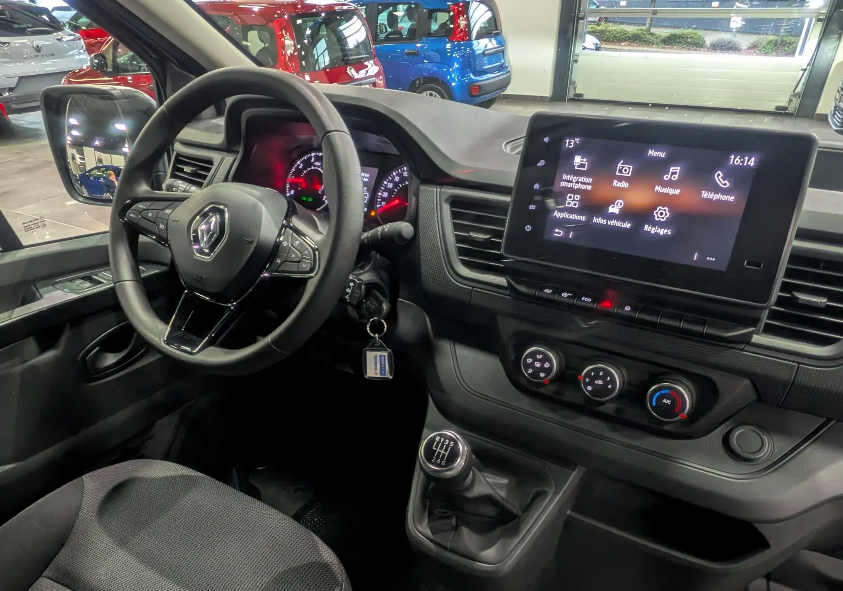 Intérieur du Renault Trafic Combi 2023 vu côté conducteur, tableau de bord noir avec écran tactile et levier de vitesse manuel.