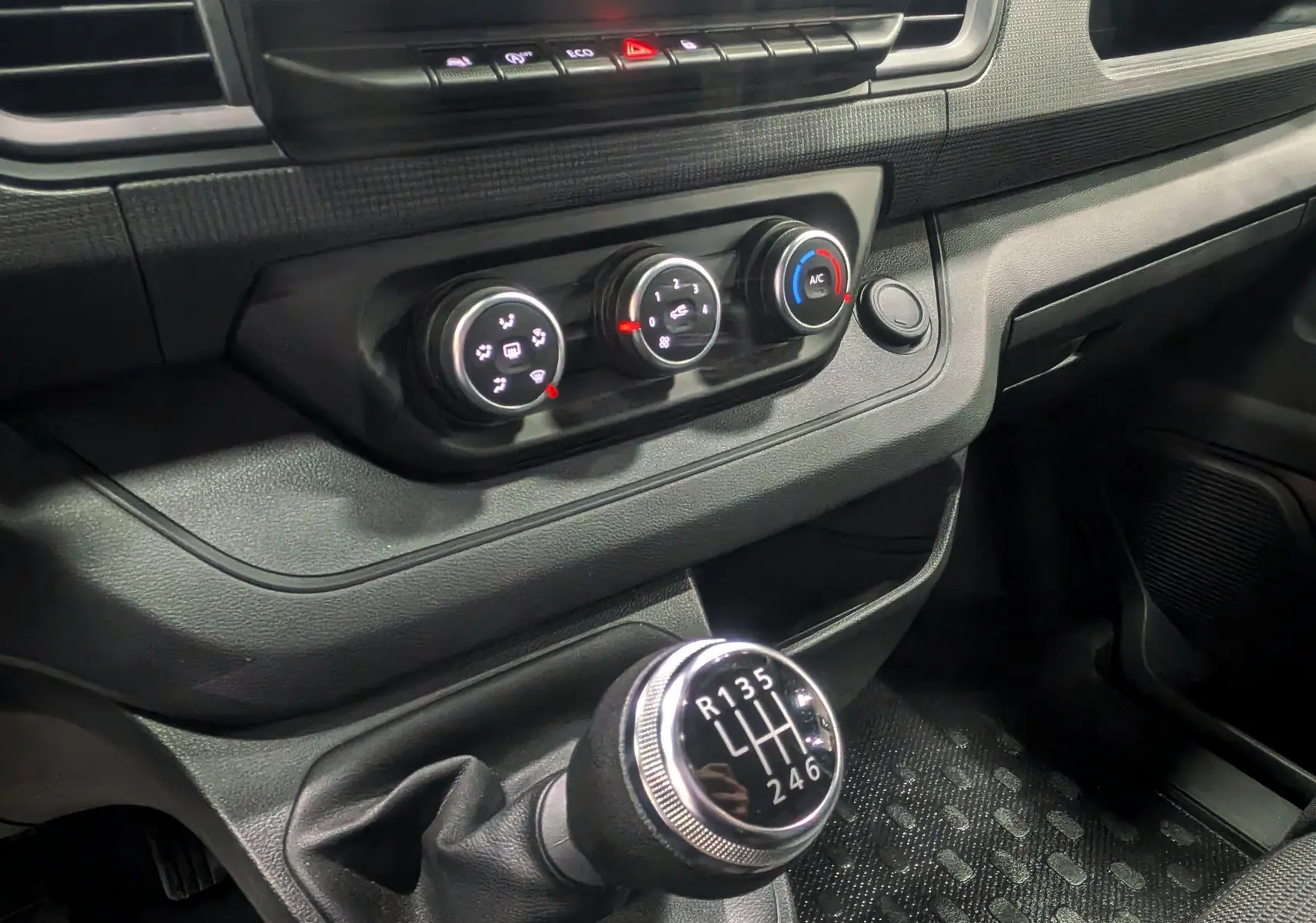 Gros plan sur la commande de boîte manuelle et les réglages de climatisation du Renault Trafic Combi gris Comète 2023.