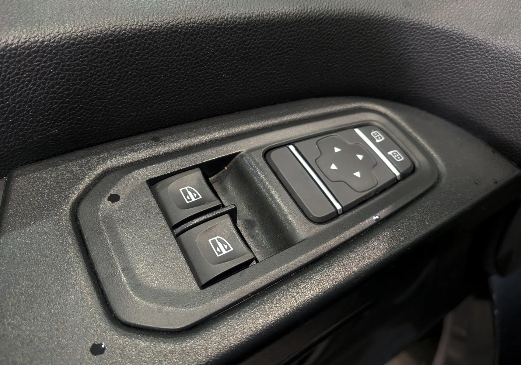 Commande électrique des vitres et réglage des rétroviseurs sur la porte côté conducteur du Renault Trafic Combi gris Comète 2023.