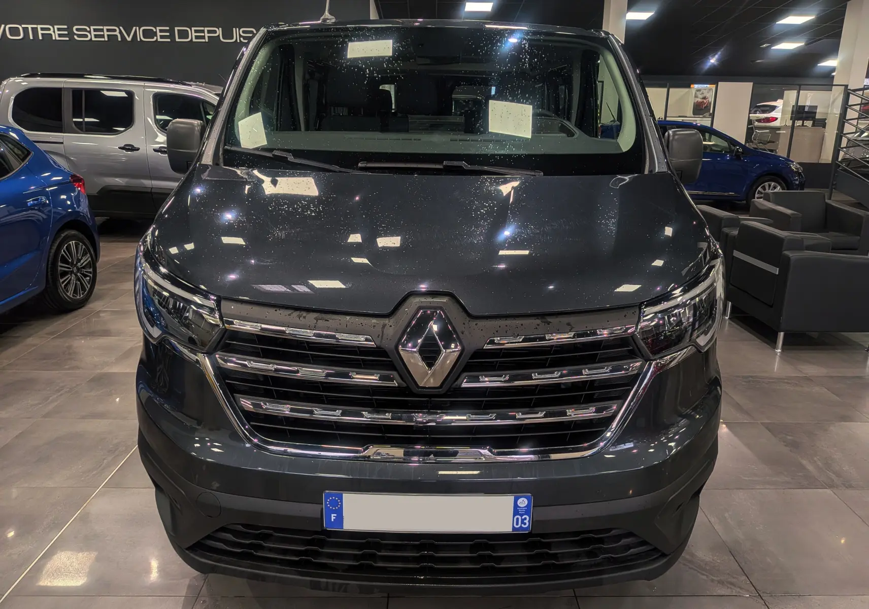 Vue de face du Renault Trafic Combi L2 dCi 150 CH ZEN 9PL gris Comète, avec calandre chromée et logo Renault bien visible.