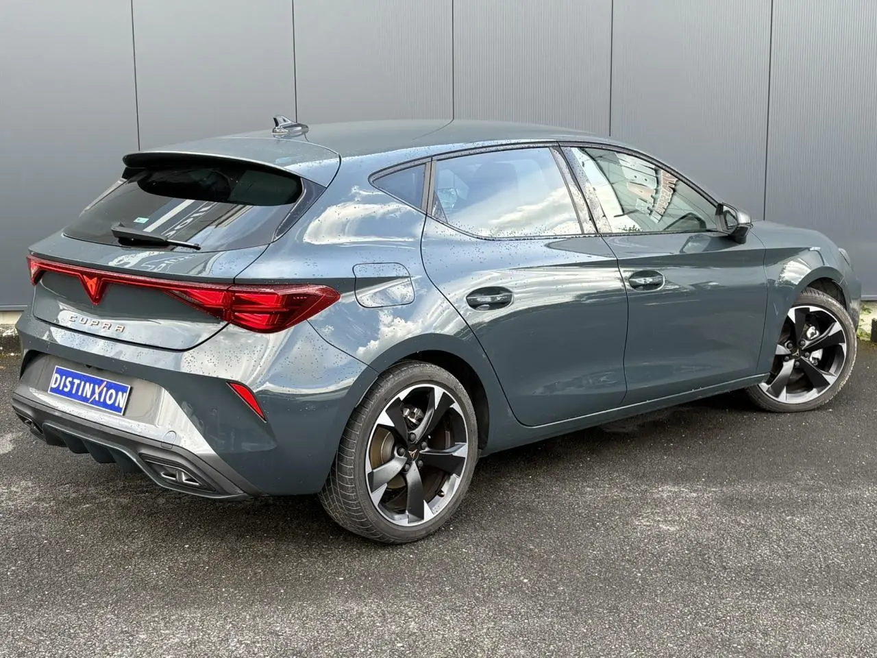 Vue 3/4 arrière droite d'une CUPRA Leon 2025 Bleu Fjord avec jantes alliage 18'' et bandeau lumineux arrière Tri-LED.