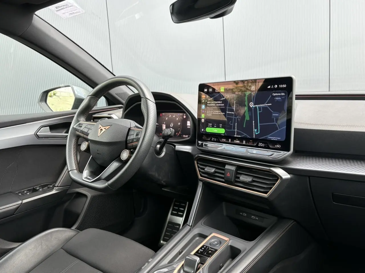 Vue intérieure côté conducteur de la CUPRA Leon 2025, tableau de bord noir avec écran tactile et volant cuir Supersports.